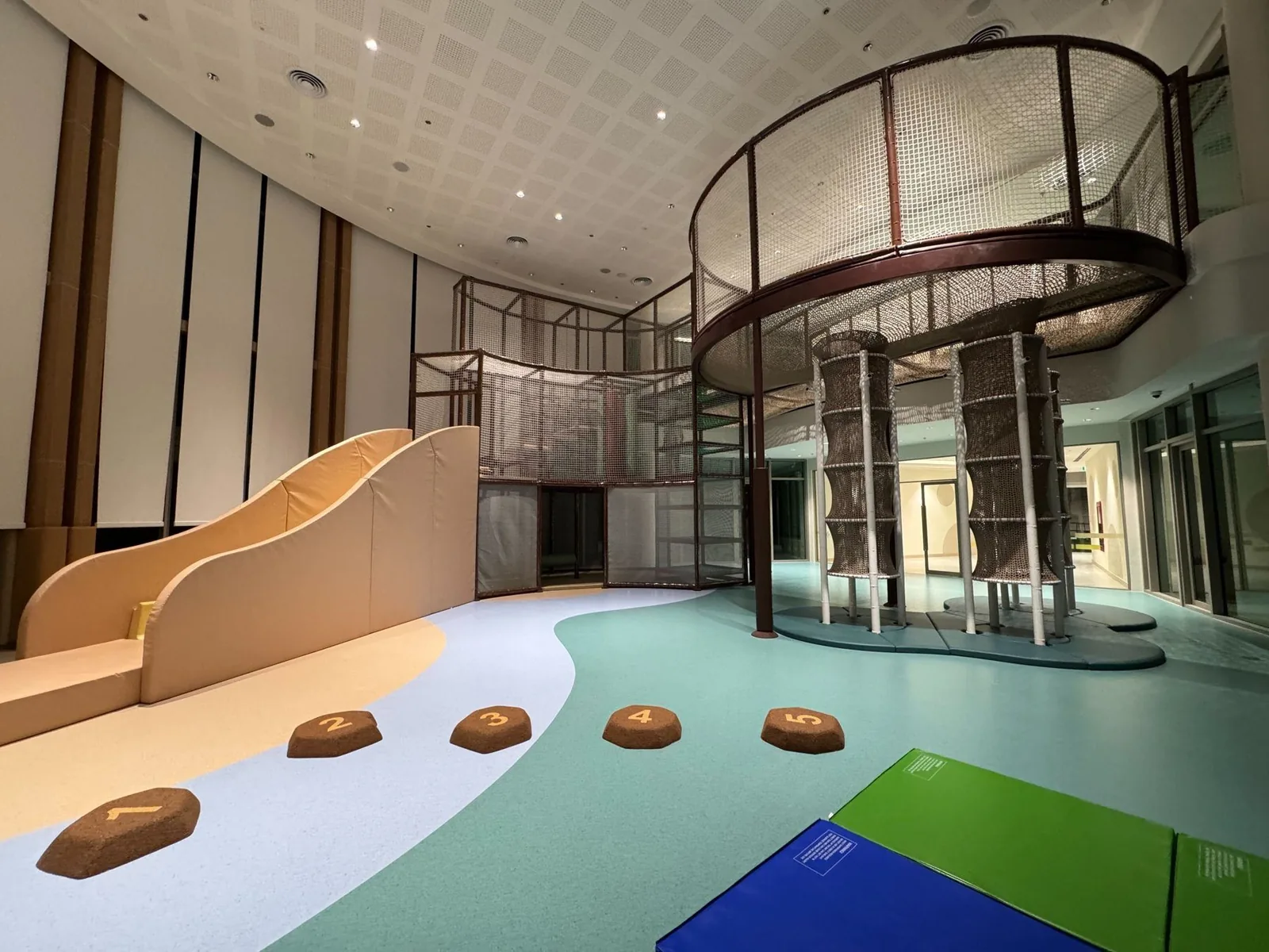The EY Jungle Gym indoor playground at KIS International School — three-level net climbing tower and twin wave slide.